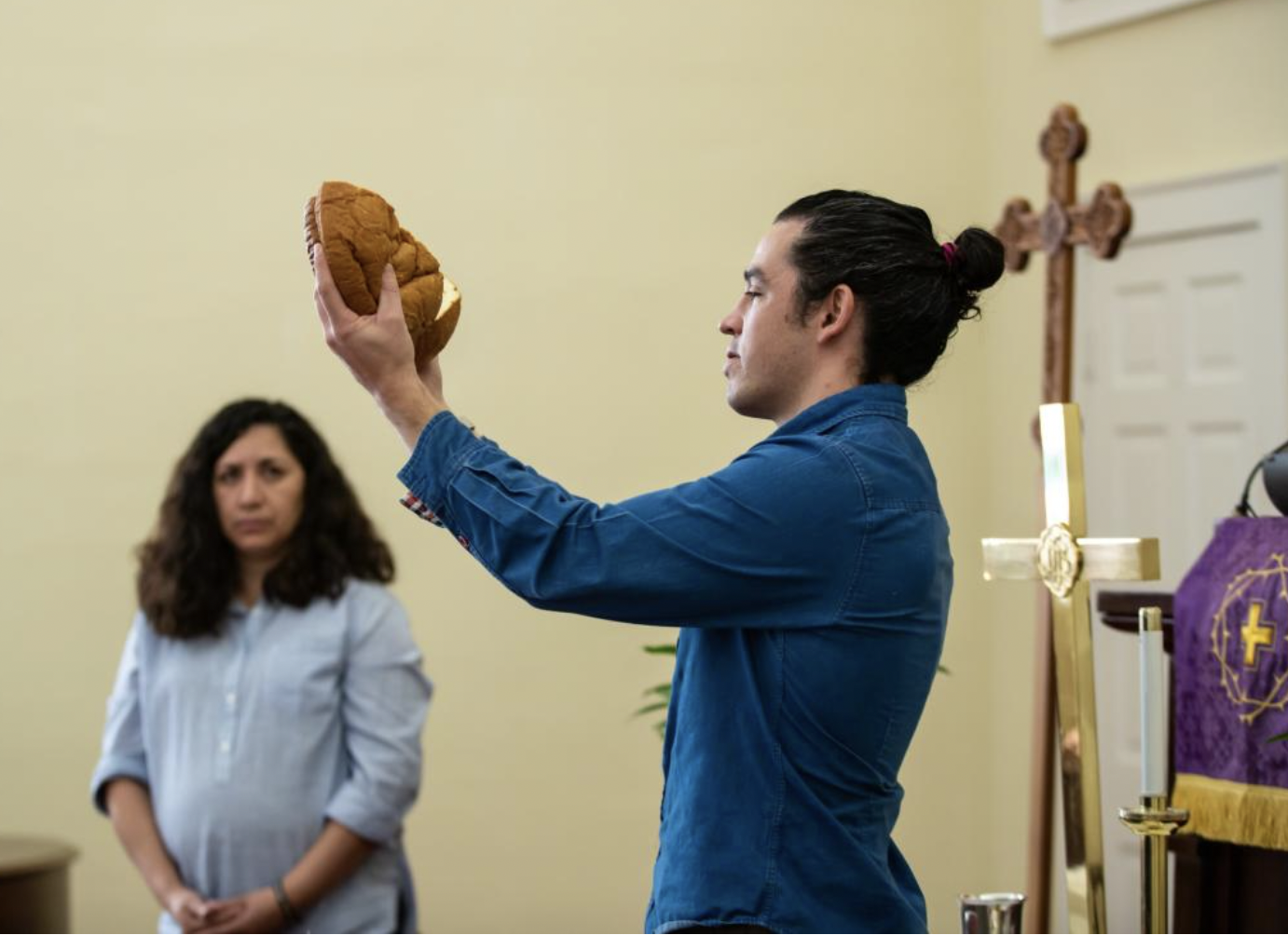 Pastor Jason Villegas holds up a loaf of bread symbolizing the body of Christ for a communion ceremony.